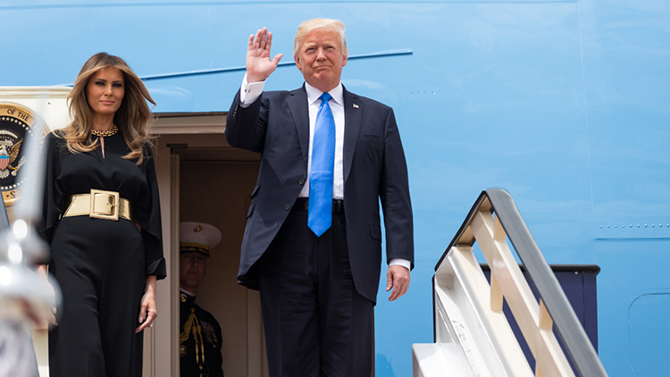 Donald Trump stands at on a plane waving for a photo opp.