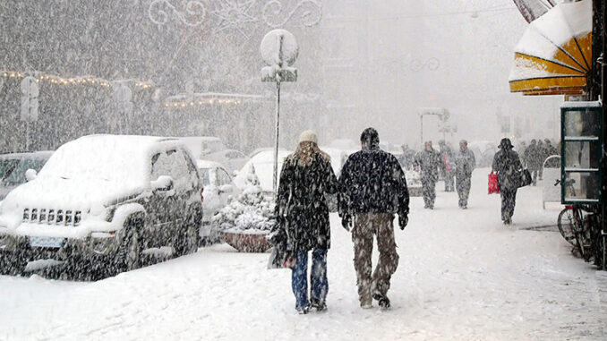 Gente caminando por las aceras de una ciudad durante una nevada.