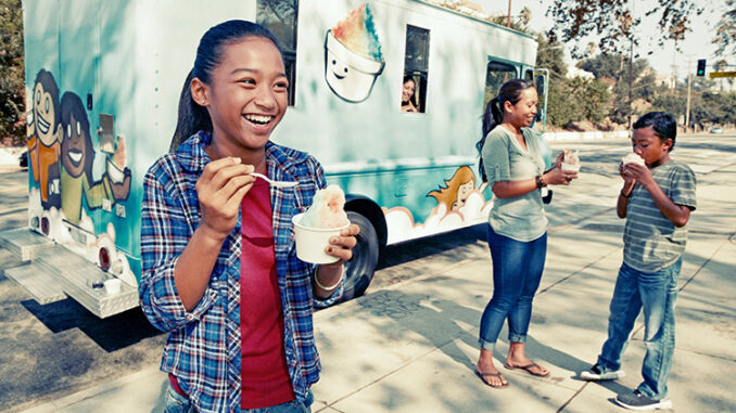 Muchacha comiendo helado de un camión.