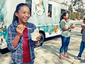 Girl eating ice cream from a truck.
